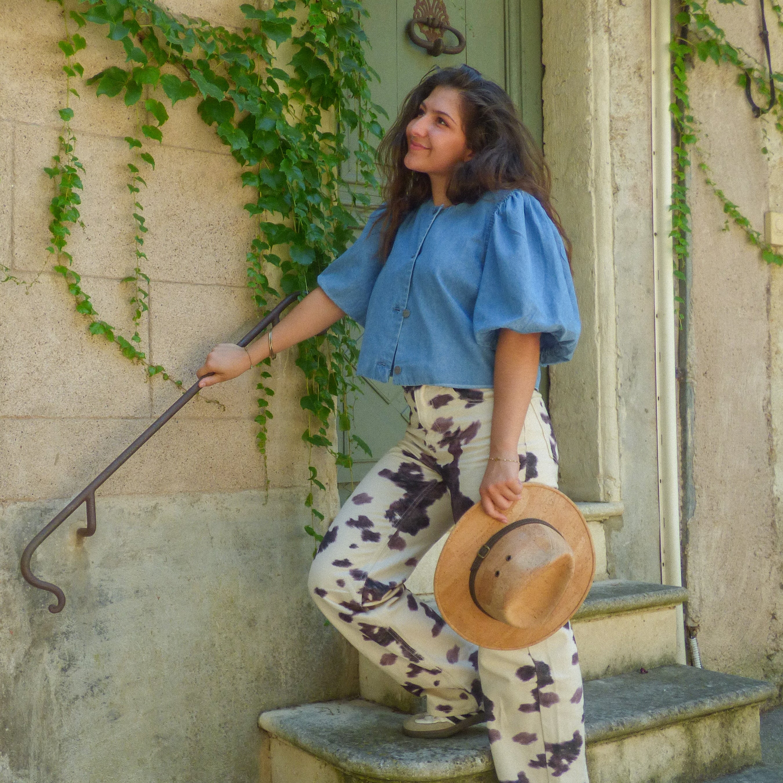 Chapeau cowboy en liège naturel tenu à la main par une femme descendant un escalier en pierre — Amador Varum, Portugal