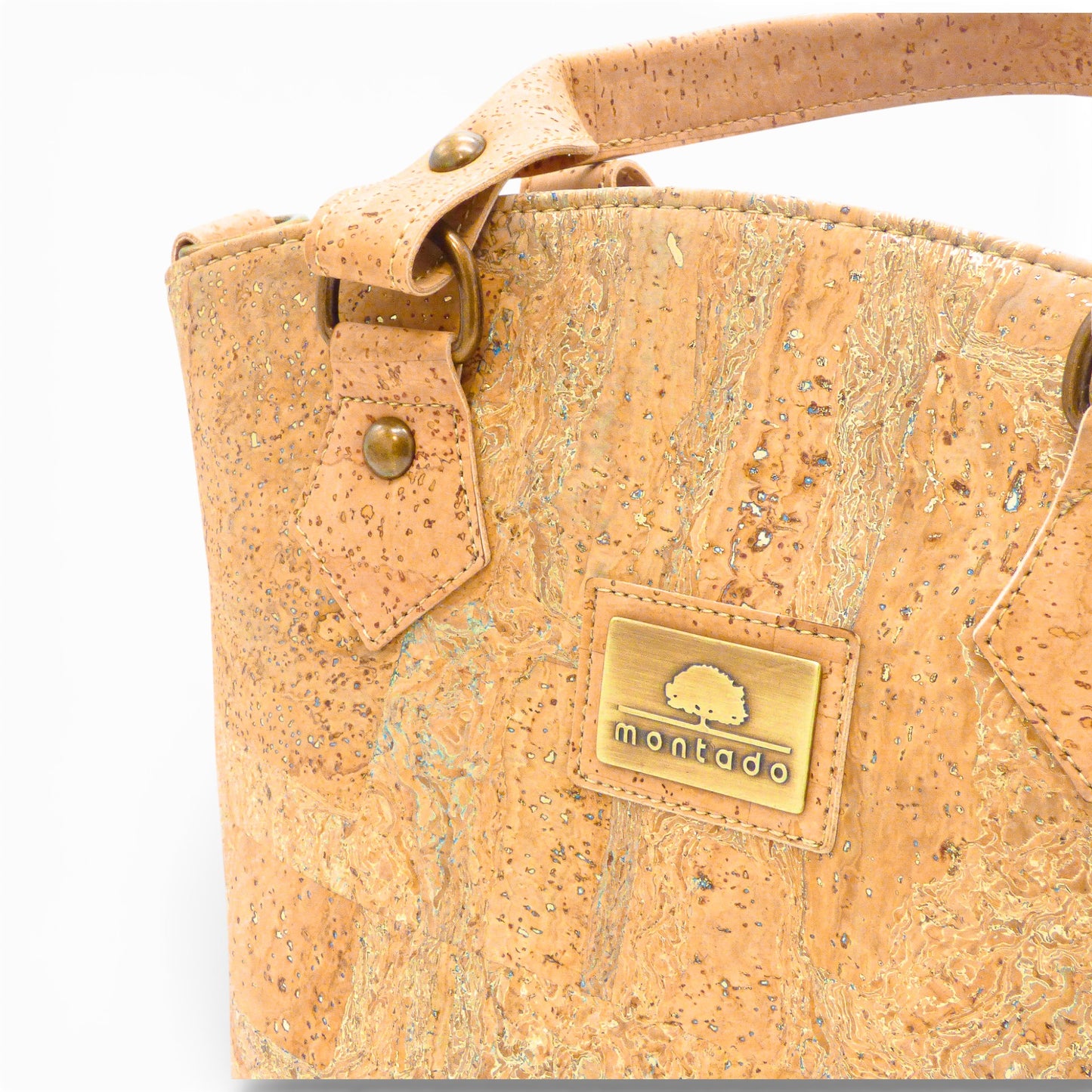 Close-up of Montado trendy cork bag showing textured cork with gold flecks and logo detail.